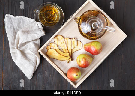 Pere essiccate con tè su un vassoio in legno, vista dall'alto. Una sana prima colazione. Lay piatto Foto Stock