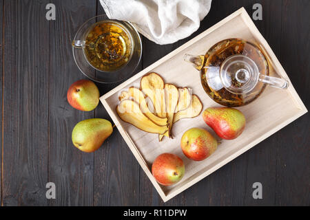 Pere essiccate con tè su un vassoio in legno, vista dall'alto. Una sana prima colazione. Lay piatto Foto Stock
