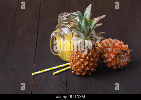 Succo di ananas e ananas collocato su un tavolo di legno Foto Stock