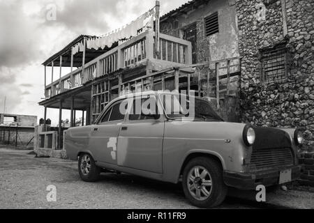 20/03/2015, Havana, Cuba: un vecchio completamente assemblati personalizzati auto è la formazione di ruggine di distanza di fronte a un vecchio edificio cubano. Foto Stock