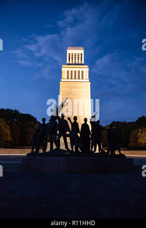 Weimar, Germania - Oktober 2018: Buchenwald Memorial belfry e le sagome del gruppo di figure di notte Foto Stock