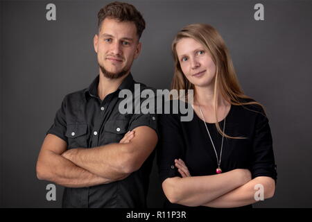 Ritratto in studio di due giovani e happy business partner in piedi con le mani incrociate a loro torace Foto Stock