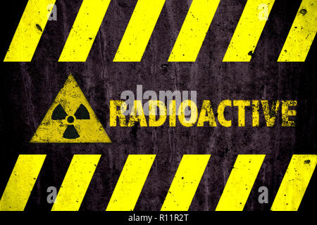 Radioattivo (radiazioni ionizzanti o energia nucleare) Pericolo simbolo e parola di colore giallo e con luci di strisce nere dipinta su un massiccio muro di cemento con Foto Stock