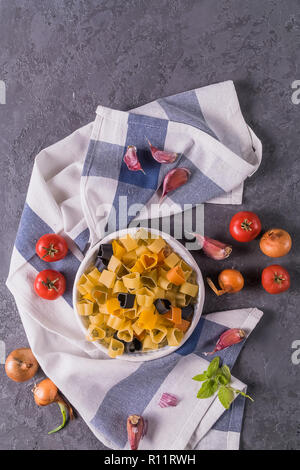 Flaat vista laici gli ingredienti per la pasta con olio di oliva cipolla, pomodoro, aglio e spezie, su grigio backgorund. Foto Stock