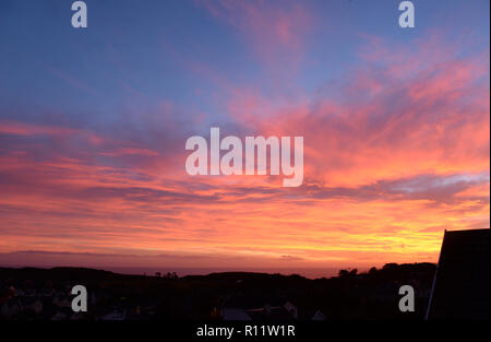 Tramonto a Mumbles. Impostazione di un sole che scompare sotto l'orizzonte causando la rifrazione atmosferica creando la bella spettro di colori nel cielo. Foto Stock