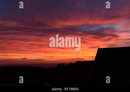 Tramonto a Mumbles. Impostazione di un sole che scompare sotto l'orizzonte causando la rifrazione atmosferica creando la bella spettro di colori nel cielo. Foto Stock