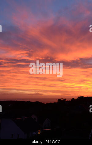 Impostazione sun in Mumbles, Gower, produce un bel cielo colorato da unico condizioni atmosferiche provocando una intensa arancione e rosso Foto Stock