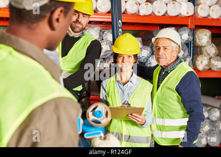 Lavoratori come una squadra logistica nel magazzino a discutere su un insieme di consegna Foto Stock