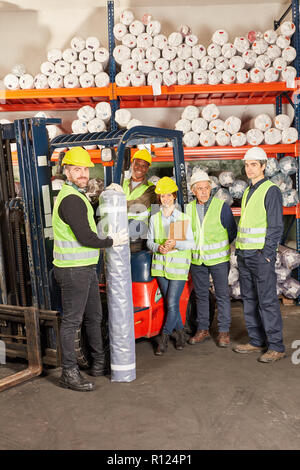 Gruppo di lavoratori di magazzino come un team con il carrello elevatore a forche in hall nel centro di spedizione Foto Stock