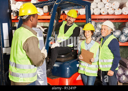 Team addetto al magazzino con il carrello elevatore in magazzino di tappeti preparare una nave Foto Stock