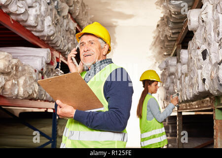 Magazzino Senior lavoratore in transito telefonare con lo smartphone in magazzino Foto Stock