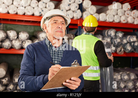 Senior come un apritoio con una lista di controllo non di inventario in magazzino Foto Stock
