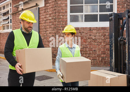 Due lavoratori logistica trasportare pacchi insieme come un servizio di consegna nel trading online Foto Stock