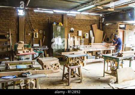 L'uomo facendo lavori in legno in falegnameria. Laboratorio di falegnameria. Carpenter lavorando su asse di legno in officina. Foto Stock
