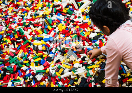 Bambina gioca con plastica molti mattoni da costruzione parti. Giocattoli educativi per bambini Foto Stock