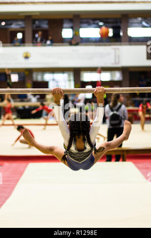 Athletic bambina ginnasta eseguire esercizi al bar in campionato Foto Stock