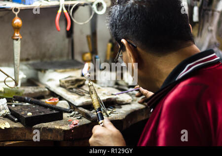 Maestro gioielliere saldatura un ornamento in un workshop di gioielli. Immagine di mani e prodotto da vicino. Foto Stock