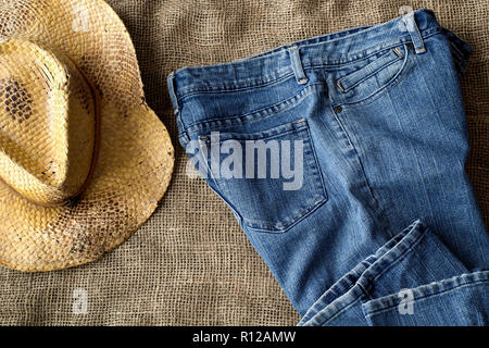 Jeans blu e in stile country cappello di paglia su tela. Vista dall'alto in basso. Foto Stock