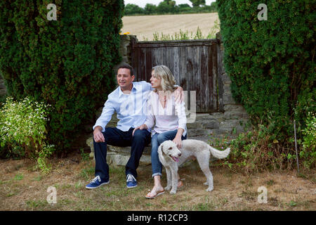 Romantico Coppia matura con il cane seduto in giardino Foto Stock