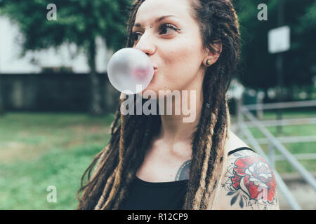 Donna soffiando bubble gum in posizione di parcheggio Foto Stock