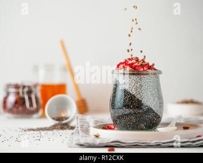 Colazione salutare concetto e idea - due colori chia pudding con materie organiche melograno. Il vasetto di vetro con il nero antracite e bianco latte vegano chia pudding con la caduta di semi di canapa. Spazio di copia Foto Stock