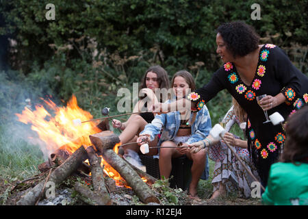 Amici tostare marshmallows al falò delle parti in posizione di parcheggio Foto Stock