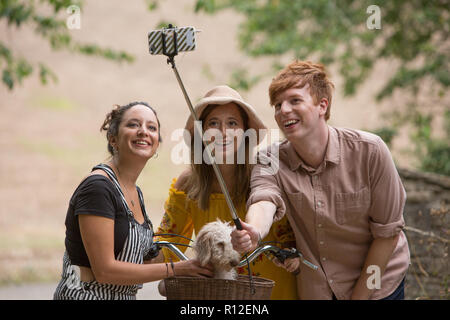 Amici prendendo selfie con cane in campagna Foto Stock