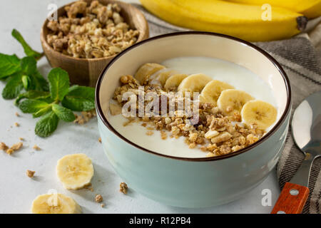 Il Granola di close-up. Muesli con yogurt, cioccolato e banana su una pietra bianca tabella. Il concetto di una sana nutrizione e dietetica. Foto Stock