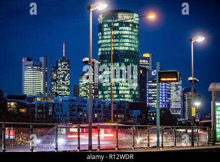 Francoforte, Germania. 08 novembre 2018, Assia, Frankfurt/Main: Il Westhafen Tower (M) sorge nella luce della sera di fronte altri grattacieli della città. I circa 110 metri alto ufficio edificio ha una forma cilindrica e triangolare di lastre di vetro sulla facciata dare l'apparenza di un tipico vino di mele di vetro per la regione. Foto: Frank Rumpenhorst/dpa Credito: dpa picture alliance/Alamy Live News Foto Stock