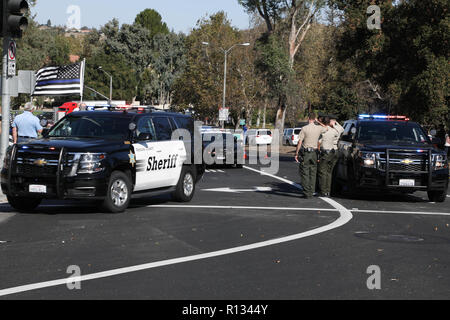 Thousand Oaks, California, Stati Uniti d'America. 8 Novembre, 2018. Ufficiali salutate la processione in onore di Sargeant Ron Helus della Contea di Ventura Sheriff's Dept., che ha sparato e ucciso durante una ripresa di massa al confine Bar & Grill a Thousand Oaks, California Mercoledì sera, lasciando 13 morti. La bandiera sulla sinistra con le strisce blu è un memoriale speciale bandiera per la caduta degli ufficiali. Credito: Sheri Determan/Alamy Live News Foto Stock