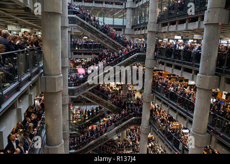 Londra, Regno Unito. 9 Nov 2018. Migliaia linea l'atrio e scale mobili al Lloyd's commemorazione servizio. Petali di papavero cadere sopra nel atriium come la bugle gioca "l'Ultimo Post' . La Lutine campana suona durante la ghirlanda di cerimonia di posa con personalità tra cui il Sindaco di Londra e il Chelsea pensionati con i 7 fucili a canna rigata che compongono la Guardia d'onore Credito: Tommy Londra/Alamy Live News Foto Stock