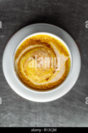 Casual caffetteria. Latte art. La formazione di schiuma del latte. Brocca in vetro chiaro. Fiori d'arancio in un bianco ovale vaso bianco. Foto Stock