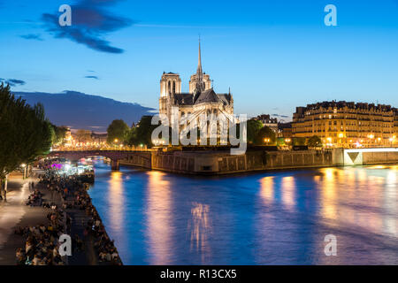 Notre Dame de Paris con la nave da crociera sul fiume Senna di notte a Parigi, Francia Foto Stock