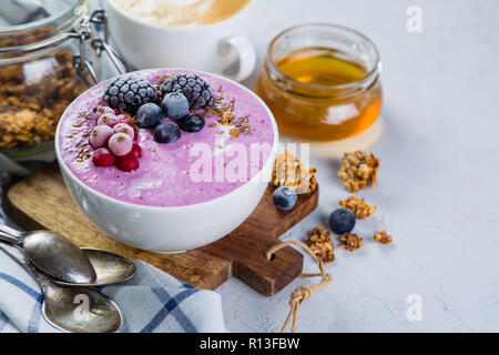 La prima colazione - yogurt ciotola con cereali e frutti di bosco, caffè, miele Foto Stock