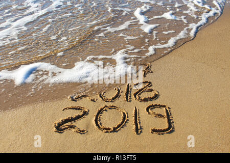 2019, 2018 e 2017 anni scritto sulla spiaggia di sabbia di mare. Wave lava via 2017, 2018. Foto Stock