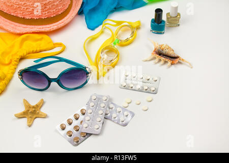 Estate womens beach accessories per la vostra vacanza al mare e pillola su sfondo bianco. Concetto di medicinali necessari in viaggio. Vista dall'alto. Lay piatto. Foto Stock