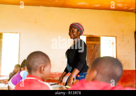 Bafoussam, Camerun - 06 agosto 2018: giovane ragazza africana maestro sorridente di volontariato durante lessonstanding fino tra i bambini Foto Stock