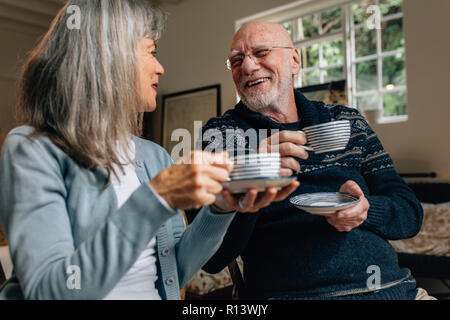 Il vecchio uomo e donna di trascorrere del tempo insieme a parlare e a bere caffè. Coppia senior seduti insieme a casa azienda tazze da caffè guardando ogni altro Foto Stock