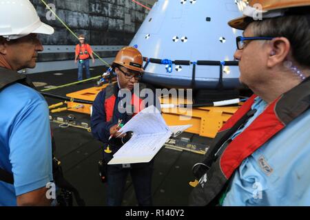 Tracy parchi, centro, con la Jacobs, serve per quanto riguarda le operazioni di recupero integratore in corso durante la prova di recupero-7 di un mock up versione di Orion la generazione successiva capsula spaziale nel pozzetto del ponte della USS John P. Murtha durante un oceano aperto prova di recupero 31 ottobre 2018 nell'Oceano Pacifico. La NASA e gli Stati Uniti La marina non ha eseguito oceano aperto il recupero di un manned space capsule poiché il progetto Apollo negli anni sessanta e sono le procedure di test e la bulloneria che verranno utilizzate per recuperare il veicolo spaziale Orion dopo che schizza verso il basso nell'Oceano Pacifico seguendo il futuro dello spazio profondo missioni di esplorazione. Foto Stock