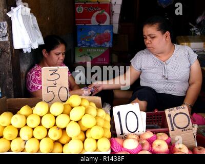 BINANGONAN, Rizal, Filippine - 8 Novembre 2018: una frutta e verdura vende fornitore di prodotti freschi presso un mercato pubblico. Foto Stock