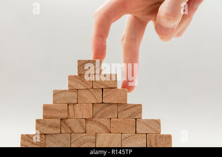 Persone mano a camminare su un insieme di blocchi di legno. Lo sviluppo del business e il concetto di crescita Foto Stock