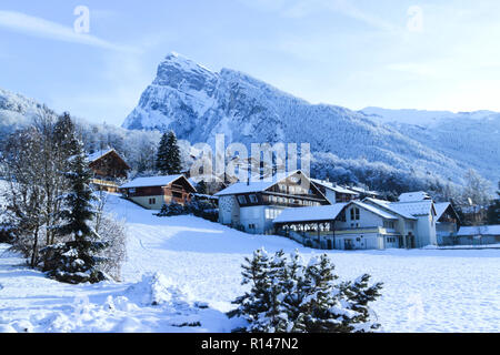 Chalet alpino coperto di neve sulle piste da una grande roccia e foresta di alberi di pino in francese sci resort . Foto Stock