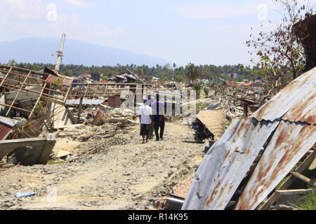 Si vedono persone che passa in corrispondenza del sito dove il terremoto è accaduto. Un mortale terremoto di magnitudo 7.5 grandezza e un maremoto distrusse la città di Palu e gran parte dell'area di Sulawesi centrale. Il numero di morti è stato 2088, circa 5000 persone sono state gravemente ferite e alcuni 62.000 persone sono state sfollate. Foto Stock