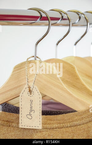 Abbigliamento organico. Colore naturale t-shirts appesi i portabiti in legno in una fila. Foto Stock