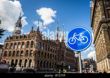 AMSTERDAM, Paesi Bassi - 7 Settembre 2018: blu percorso ciclo segno; Magna Plaza Shopping Mall in background Foto Stock