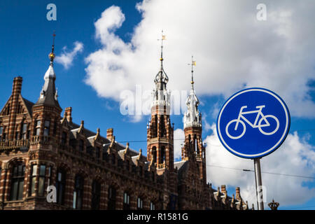 AMSTERDAM, Paesi Bassi - 7 Settembre 2018: blu percorso ciclo segno; Magna Plaza Shopping Mall in background Foto Stock