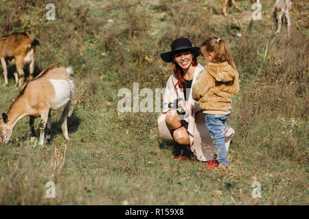 La madre cammina con piccola figlia nei pressi di un allevamento di capre in autunno Foto Stock