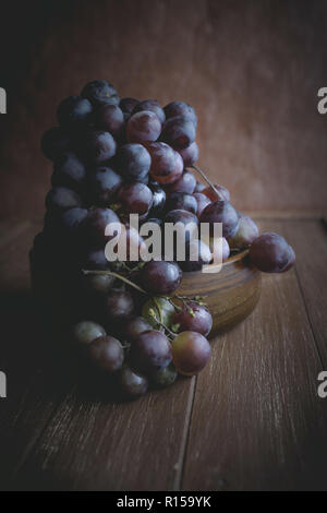 Le uve rosse giacente in una ciotola di legno Foto Stock