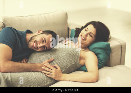 Un futuro felice papà di ascolto il ventre di sua moglie incinta mentre vi rilassate sul divano di casa Foto Stock