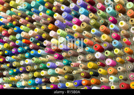 Parete organizzato di bobine con fili di cucitura in molte variazioni di colore Foto Stock